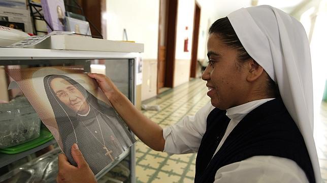 Una joven monja sostiene una imagen de Madre Lupita