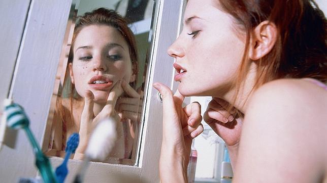 Una adolescente se observa un grano