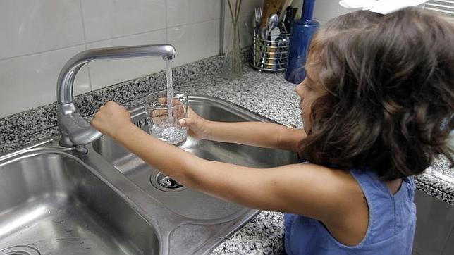 Una niña llena un vaso con agua del grifo