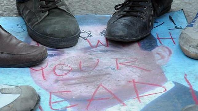 Un grupo de ciudadanos pisa una fotografía de Mubarak en la plaza Tahriri de El Cairo