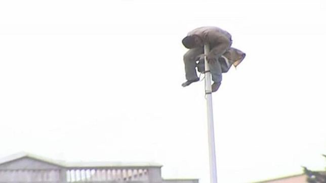 En video: Un inmigrante se sube a una farola junto a la valla durante horas