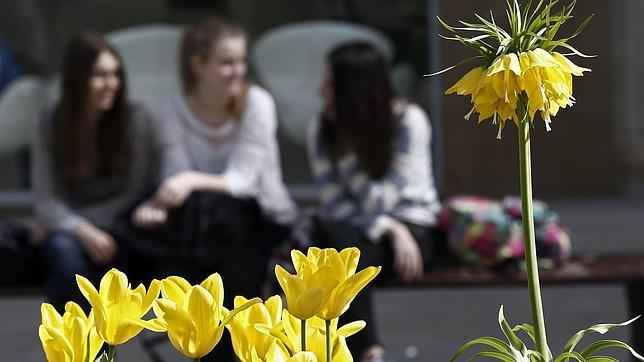 Jóvenes descansan en un banco del Paseo de Pamplona