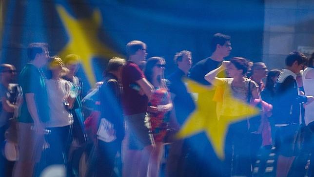 Ciudadanos reflejados detrás de la bandera de la UE, en Bruselas