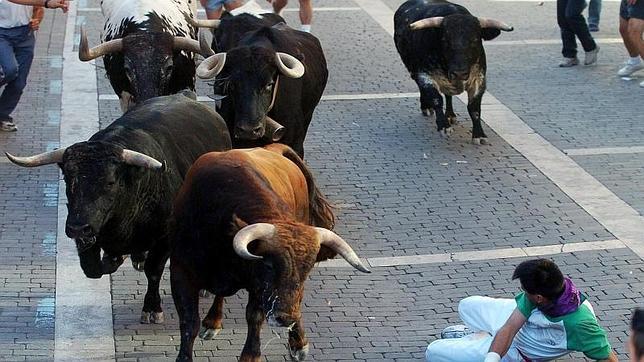 Hombre caído ante varios toros