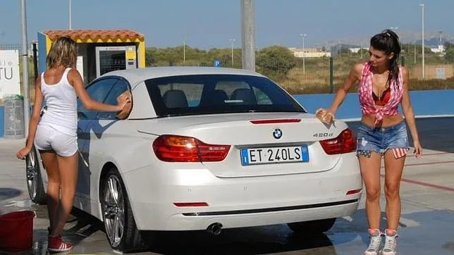 Dos modelos lavan coches de forma insinuante para promocionar un lavadero en Cerdeña