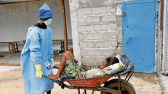 Un hombre empuja una mujer en una carretilla por ser una posible infectada al Hospital Island en Monrovia, Liberia