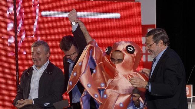 Carlos Capio disfrazado de pulpo alza el brazo de Gómez al lado de Jaime Lissavetsky y José Blanco