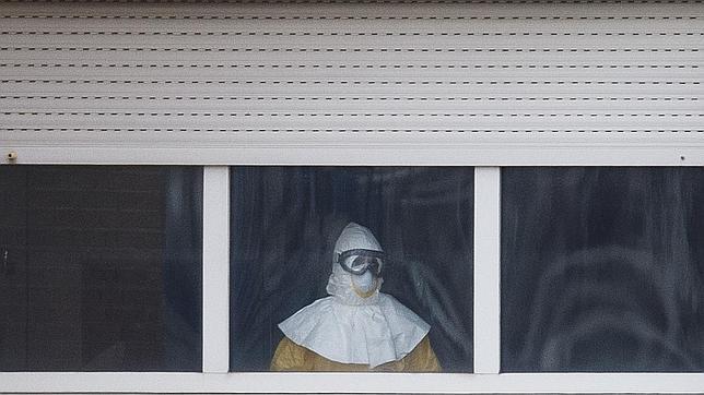 Un trabajador con el equipo de protección individual mira a la ventana desde el hospital Carlos III