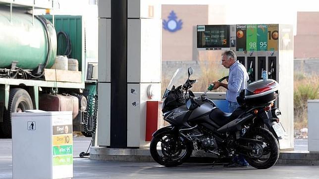 Un cliente rellena el depósito de su moto en una estación de servicio