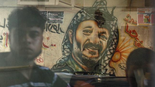 El cristal de una tienda en la Ciudad de Gaza refleja una pintada con el rostro de Arafat