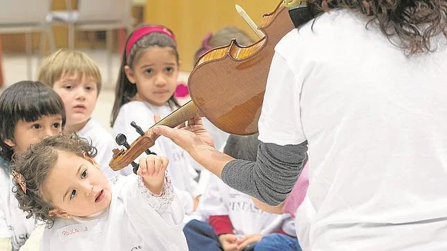 Una niña mira fascinada como toca Virginia la viola en el taller-guardería