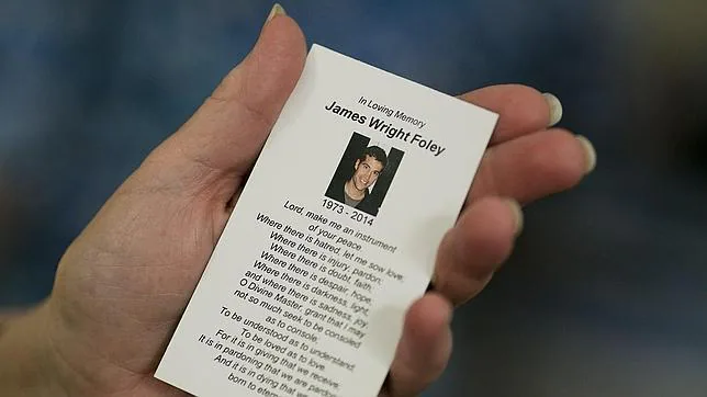 Un asistente a la misa por Foley sostiene una tarjeta en su recuerdo
