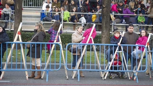 Varias familias instalan a los niños en escaleras plegables, para que vean mejor el desfile