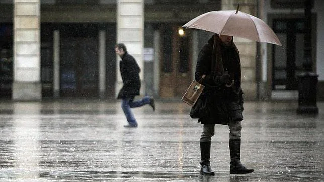 Varias personas caminan bajo la lluvia por la plaza de María Pita, en La Coruña