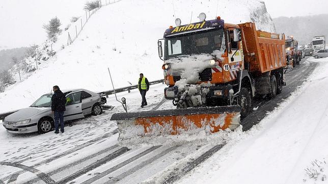 Una maquina quitanieves detenida junto a un vehiculo accidentado que ha provocado el corte de la A-67 que une Cantabria con la Meseta, afectada por las intensas nevadas que han caido las últimas horas
