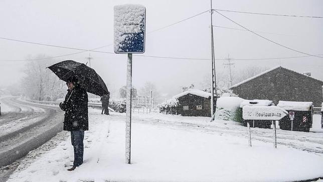 Un hombre espera al autobús en el alto de Artxanda, en Bilbao (Vizcaya) donde las fuertes nevadas están provocando importantes retenciones en el tráfico de vehículos