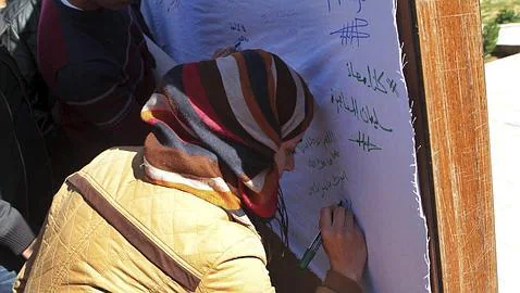 La madre del piloto, firma una pancarta por su liberación en un acto en la Universidad Jordana de Muath, en Amán