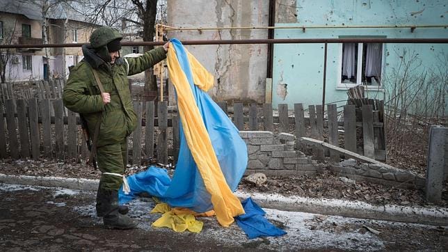 Un rebelde prorruso recoge del suelo una bandera ucraniana en Vuglegirsk