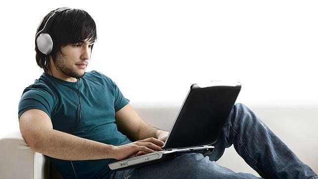 Un joven escucha música mientras trabaja con el ordenador