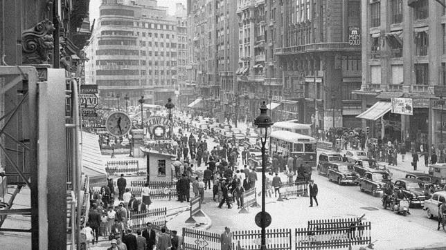 Numerosos viandantes contemplan las obras de la Gran Vía, entonces llamada avenida de José Antonio.