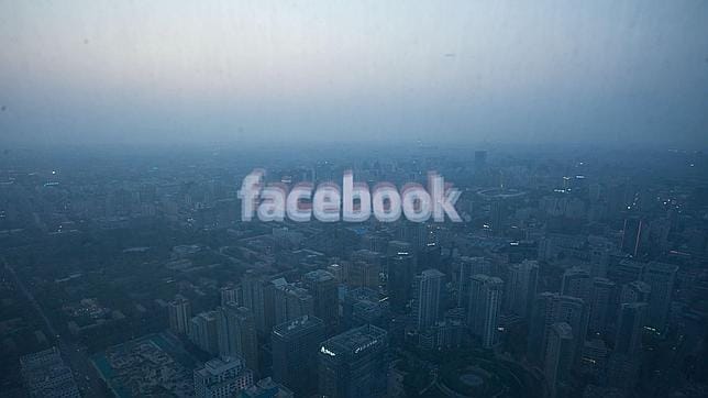 El logotipo de Facebook se refleja en una ventanal con la panorámica de Pekín