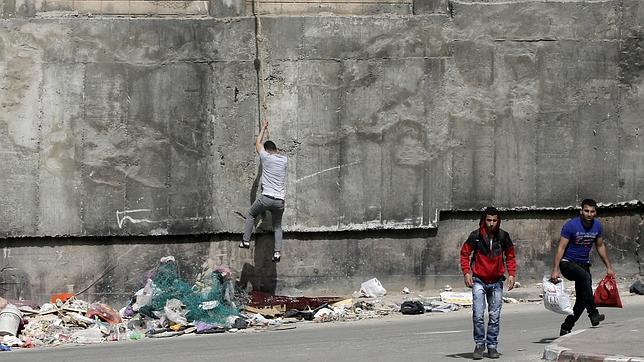 Un palestino baja desciende con un cinturón de un muro israelí en Beit Hanina, la zona disputada de Jerusalén Este
