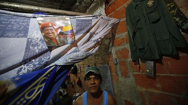 Un vecino de un barrio marginal de Caracas exhibe un cartel de Chávez
