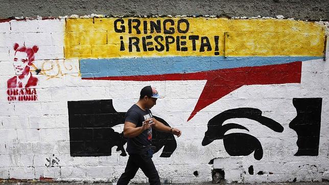 Un transeúnte pasa junto a un grafiti crítico con EE.UU. en una calle de Caracas