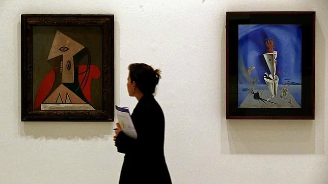 Una mujer pasa ante «Mujer en sillón rojo», de Picasso, y «Aparato y mano», de Dalí