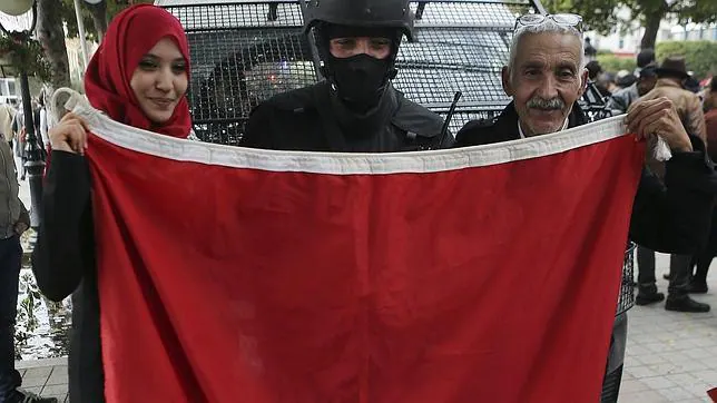 Un agente de policía tunecino posa con la bandera nacional