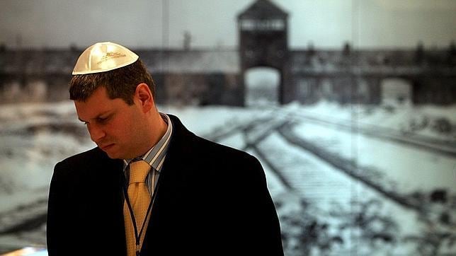Un judío con una fotografía al fondo del campo de exterminio nazi Auschwitz II-Birkenau, en 2005