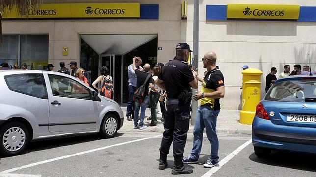 Un polícia conversa con un hombre hoy ante la sede de Correos de Melilla