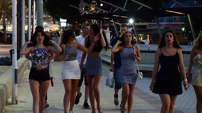 Un grupo de chicas camina por Punta Ballena (Magaluf), detrás sus amigos llevan bolsas con alcohol