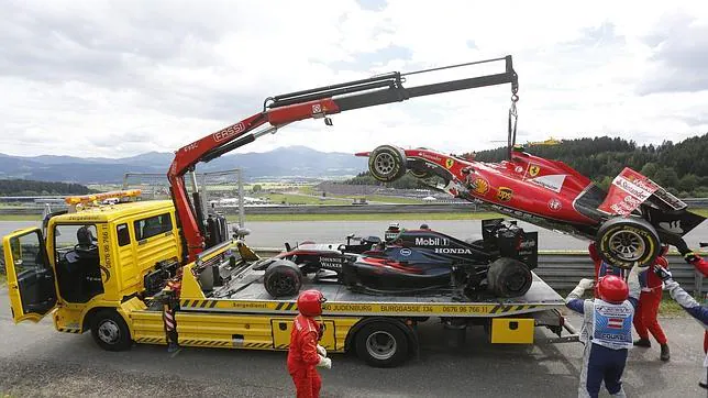 Una grúa rescata los coches de Alonso y Raikkonen después del accidente