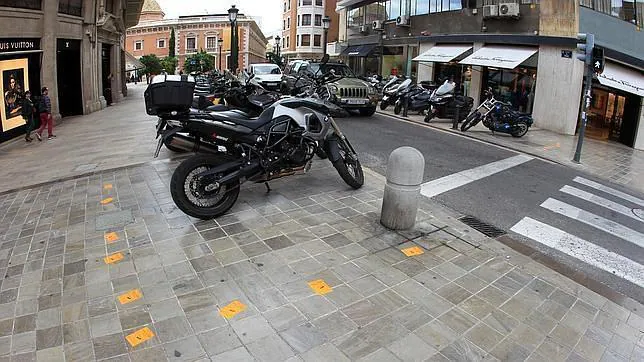 Imagen de varias motos estacionadas en la acera en el centro de Valencia