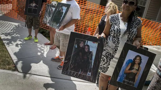 Fans de Whitney Houston y de su hija sostienen fotos de ambas a las afuras del cementerio donde se ha celebrado el entierro de la joven