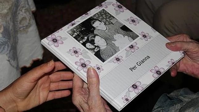 La mujer de 91 años sostiene un album de fotos de su hija, a la que no veía hace 70 años