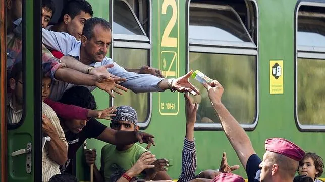 Un policía entrega zumo y frutas a los refugiados en la estación ferroviaria de Bicske (Hungría), hoy, 4 de septiembre de 2015