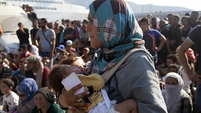 Una mujer refugiada junto a dos bebés en la isla de Lesbos, Grecia