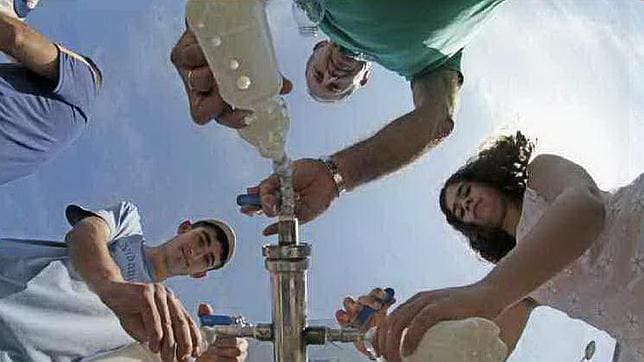 Vecinos de Santiago recogen leche regalada por los ganaderos de una cisterna