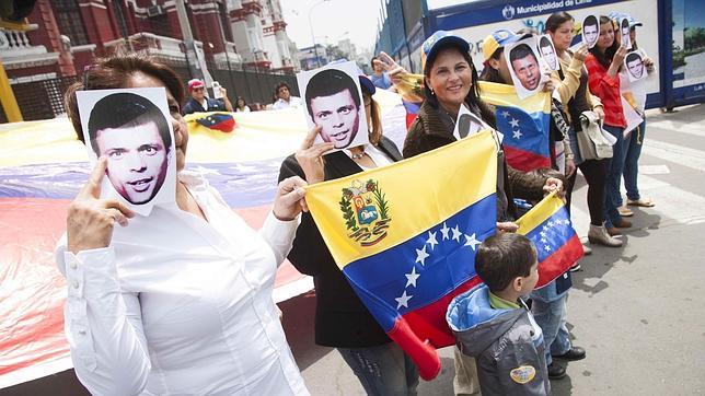 Un grupo de personas provistas con banderas venezolanas e imágenes de Leopoldo López