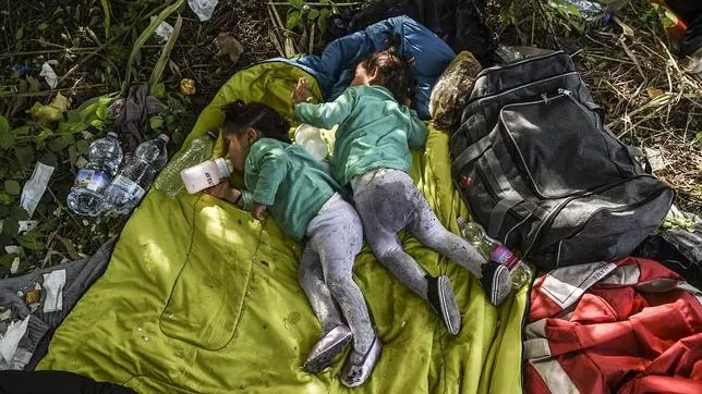 Dos niños refugiados duermen en la frontera entre Serbia y Hungría
