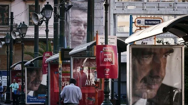 Un hombre camina entre los carteles electorales de Tsipras y Meimarakis en Atenas