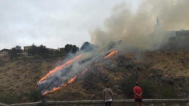 Dos paseantes observan el fuego en los rodaderos que bajan desde la Academia de Infantería