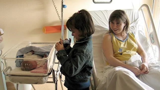 Imagen de archivo en la que aparece un bebé junto a su madre y su hermana en un hospital