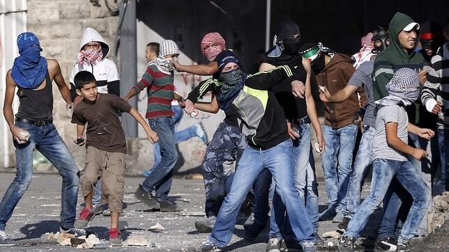 Manifestantes palestinos lanzan piedras a las fuerzas israelíes junto al campo de refugiados de Shuafat, al este de Jerusalén