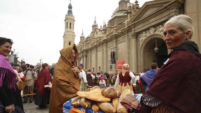 Participantes llevando alimentos ante la Virgen del Pilar en la multitudinaria Ofrenda de Frutos