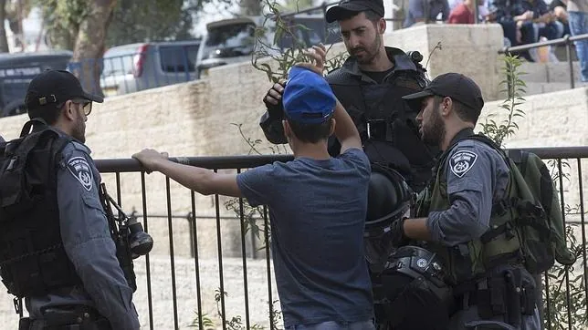 Un policía israelí cachea a un joven palestino en Jerusalén