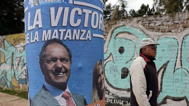 Un hombre pasa por delante de un cartel propagandistico del candidato Daniel Scioli
