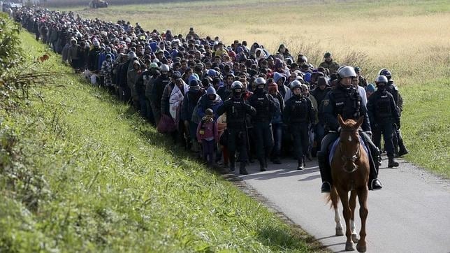 Un policía dirige a un grupo de refugiados cerca de Dobova, en Eslovenia